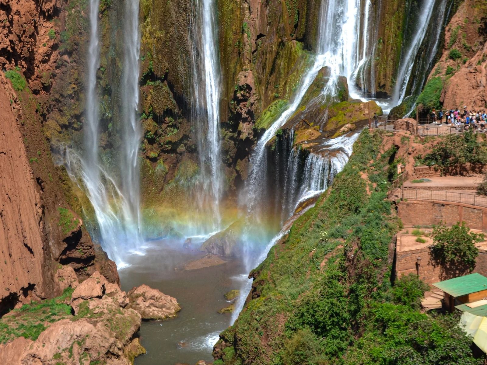 Rainbow in the spray above the pool at the foot of the Ouzoud Waterfalls, with visitors on the terraces