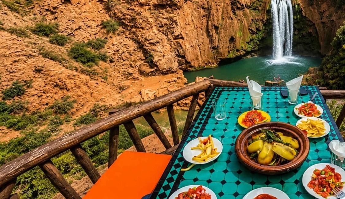 A table set with tagine and salads on a terrace facing the Ouzoud falls